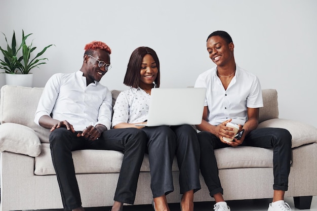 Удобный диван с ноутбуком Группа афроамериканских деловых людей, работающих вместе