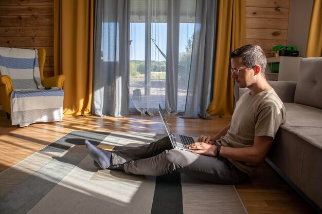 Comfortable work from home A man is sitting and working on the floor in a sunny loft apartment Home office