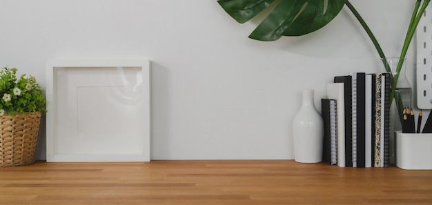 Photo comfortable workplace with mock up frame, decorations and copy space on wooden table and white wall