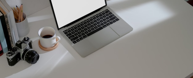 Photo comfortable workspace with  laptop, coffee cup, camera, stationery and copy space on white desk