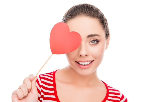 Comic smiling woman hiding her eye behind red paper heart