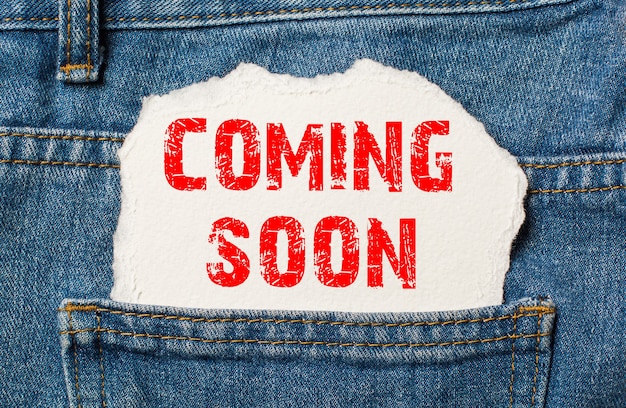 Coming Soon on white paper in the pocket of blue denim jeans