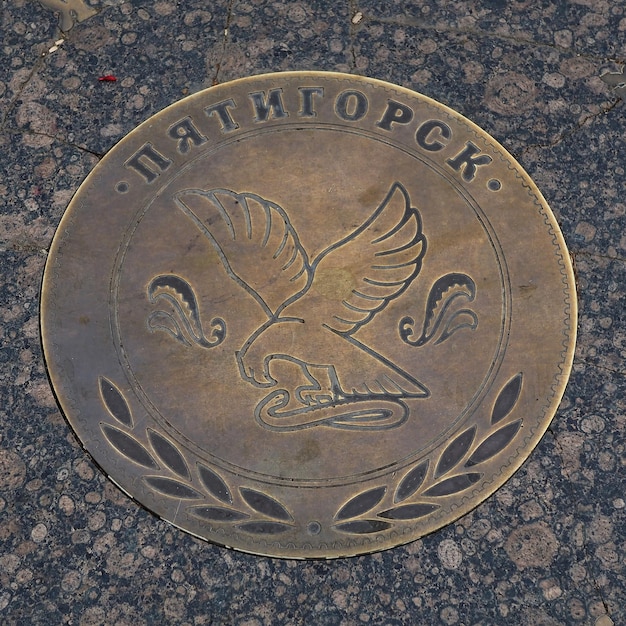 Памятный бронзовый знак Пятигорск Пятачек, замурованный в гранитную плиту на городской улице.