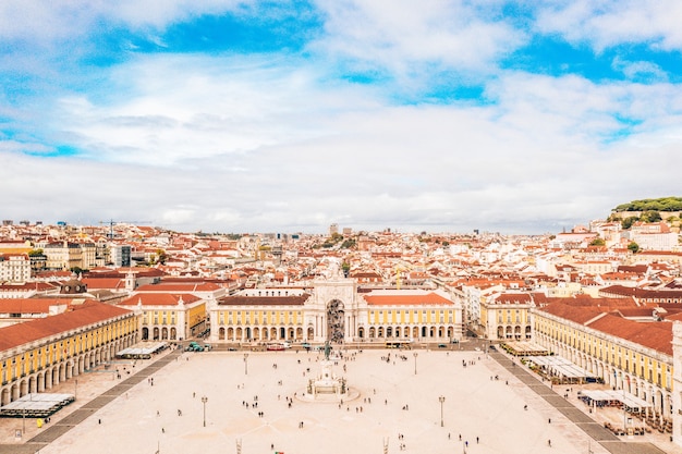 Piazza del commercio di lisbona con i turisti e i tetti arancioni degli edifici sotto il cielo nuvoloso