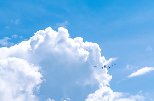 写真 青い空と白いふわふわした雲の上を飛ぶ商用航空会社晴れた日に飛ぶ飛行機