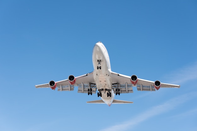 Commercial airplane flying in blue sky, full flap and landing gear extended