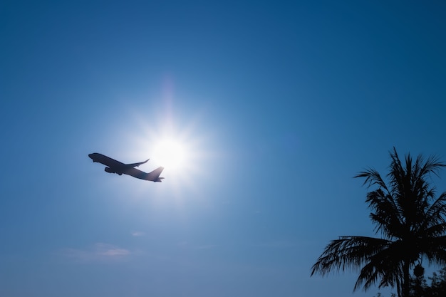 Commercial airplane flying above clouds through sunlight and beautiful blue sky.