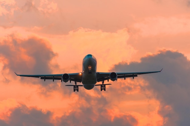 Commercial airplane flying runway airport above dramatic clouds.