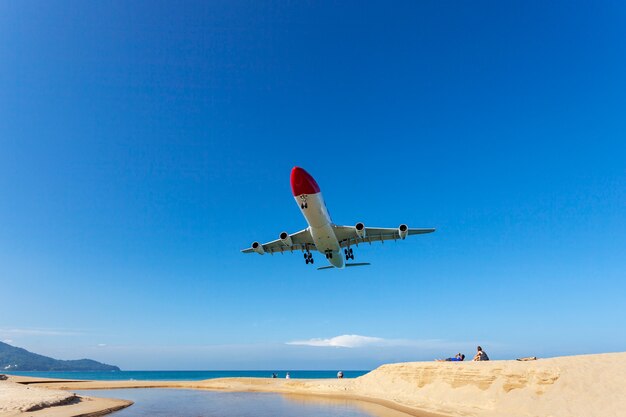 Commercial airplane landing above sea and clear blue sky over beautiful scenery nature  location at mai khao beach phuket thailand,