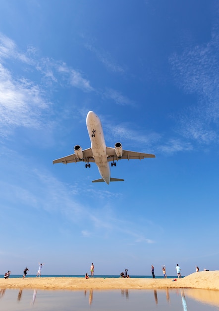 Commercial airplane landing above sea and clear blue sky 