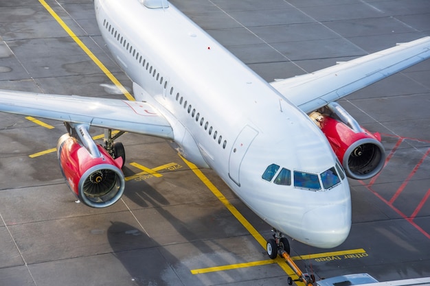 Commercial airplane parking at the airport sunlit, top view.