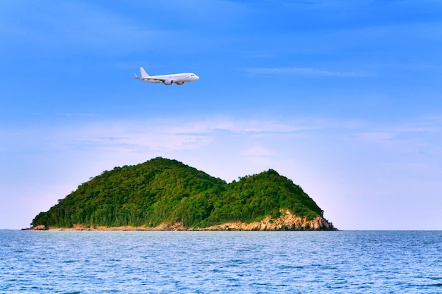 Commercial airplane above sea with island in summer season and clear blue sky over beautiful scenery ocean background Concept business travel and transportation summer vacation travel