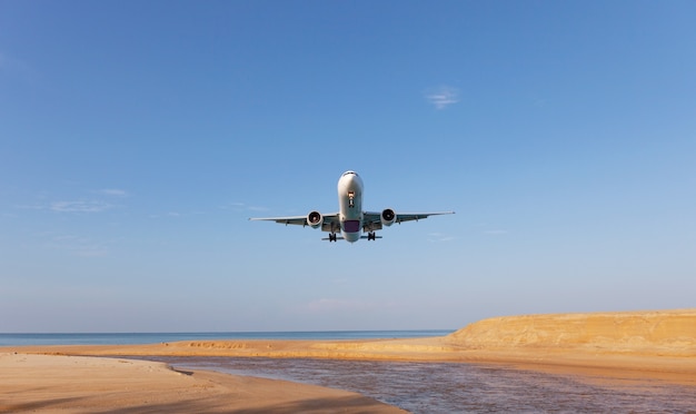 Commerciële vliegtuig landing boven zee in het zomerseizoen en heldere blauwe lucht boven een prachtig landschap