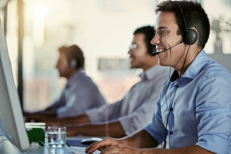 Photo committed to quality customer support cropped shot of a call centre agent working in an office with his colleagues in the background