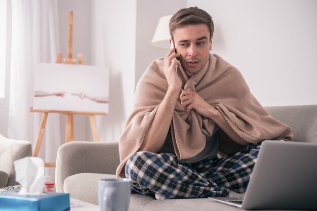 Communicatie op afstand. Ongelukkig zieke man om thuis te zitten tijdens het gesprek met zijn vriend