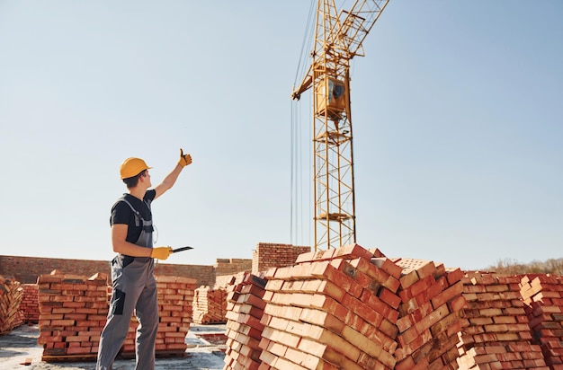 Communicating with crane guy Construction worker in uniform and safety equipment have job on building