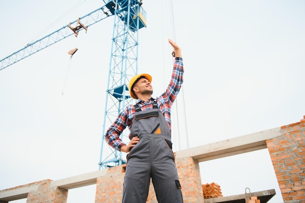 Communicating with crane guy Construction worker in uniform and safety equipment have job on building