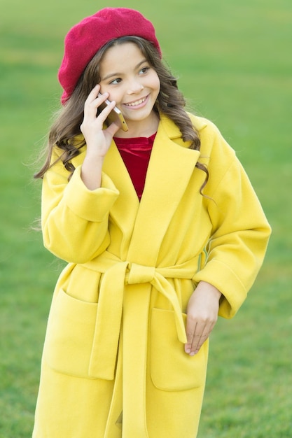 Communication concept parisian girl kid in french beret speak on phone autumn fashion fall season happy childhood small child with phone beauty in autumn coat cheerful little girl in coat