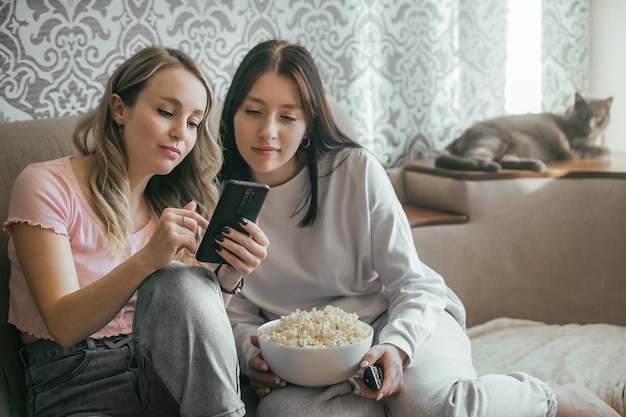 Communication of girls in a warm home environment with popcorn\
and phone