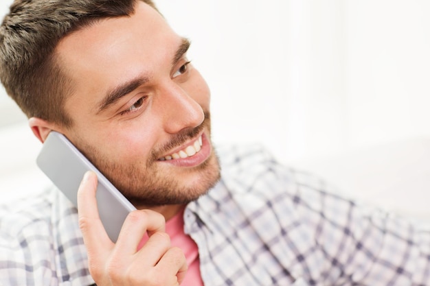 communication, technology and people concept - smiling young man calling on smartphone