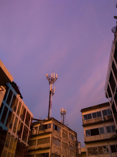 Photo the communication tower behind a commercial building in twilight time