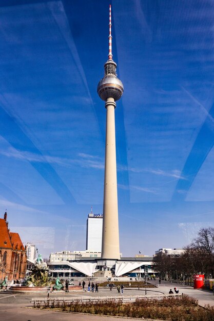 Communications tower in city against blue sky