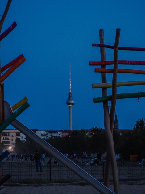 Communications tower in city against clear blue sky