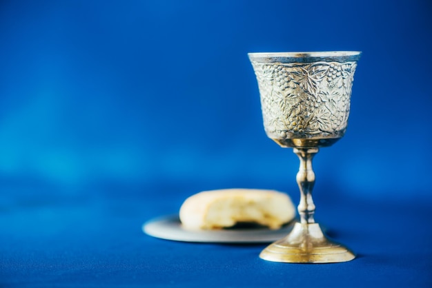 Foto communie stilleven ongezuurd brood kelk van wijn zilveren kiddush wijnbeker op blauwe achtergrond christelijke communie concept voor herinnering aan jezus offer pasen