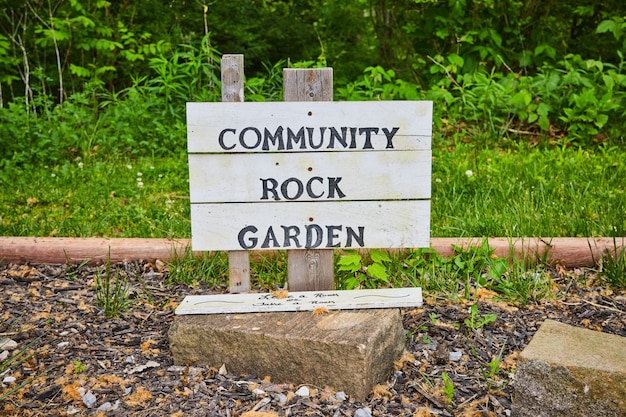 写真 コミュニティ・ロック・ガーデン (community rock garden) の白い看板で,落ちたleave a rockまたはtake a rockの看板が公園に描かれています.