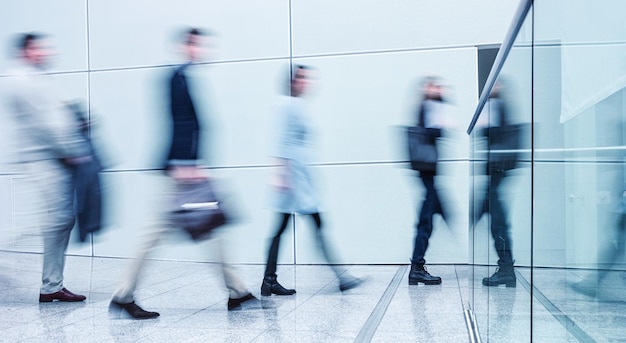 Commuters walking on corridor at a business center with motion blur. ideal for websites and magazines layouts