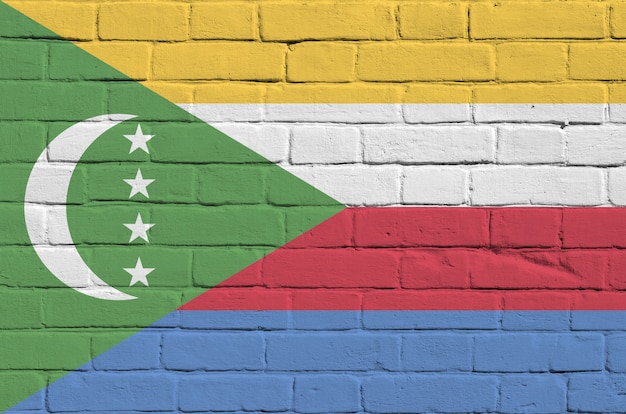Comoros flag depicted in paint colors on old brick wall. Textured banner on big brick wall masonry background