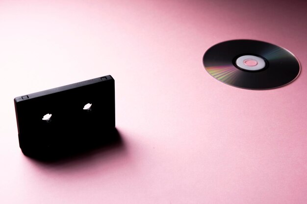 Photo compact disc and tape cassette on pink background