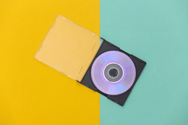 Compact disc with box on yellow blue background. Top view, minimalism