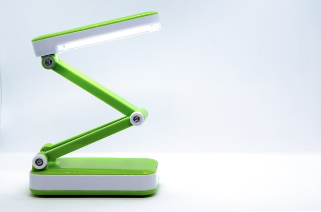 Lampada da scrivania a led portatile pieghevole compatta con corpo flessibile in plastica verde brillante su fondo bianco.