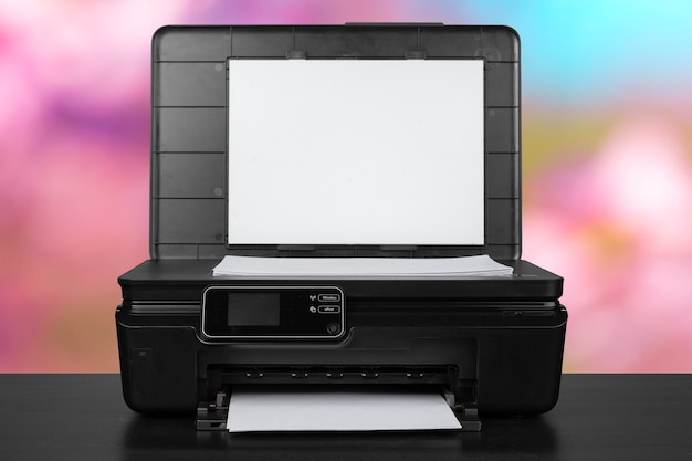 Photo compact laser printer on black desk against blurred background