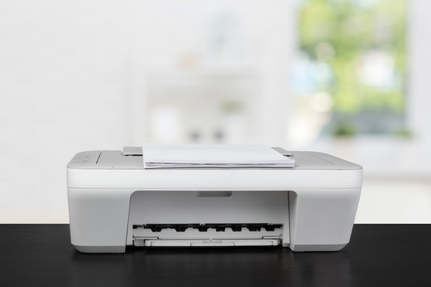 Compact laser printer on black desk against blurred background