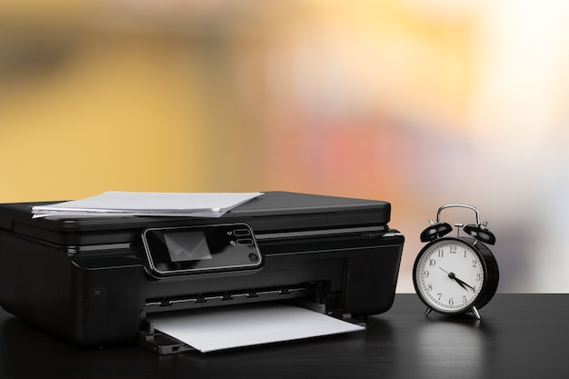 Photo compact laser printer on black desk against blurred background