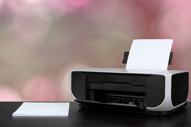 Compact laser printer on black desk against blurred background