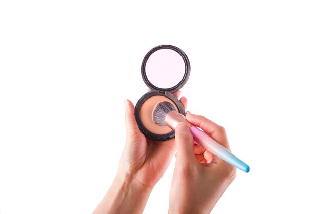 Compact powder with a mirror in the hands of a young girl close