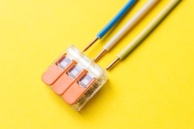 Compact splicing connector with wires phase, zero, ground on yellow background. Electronic component