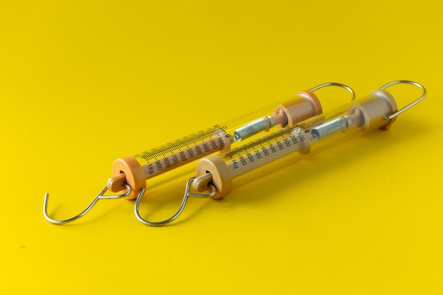 Compact spring balancer with hook Isolated on yellow background.