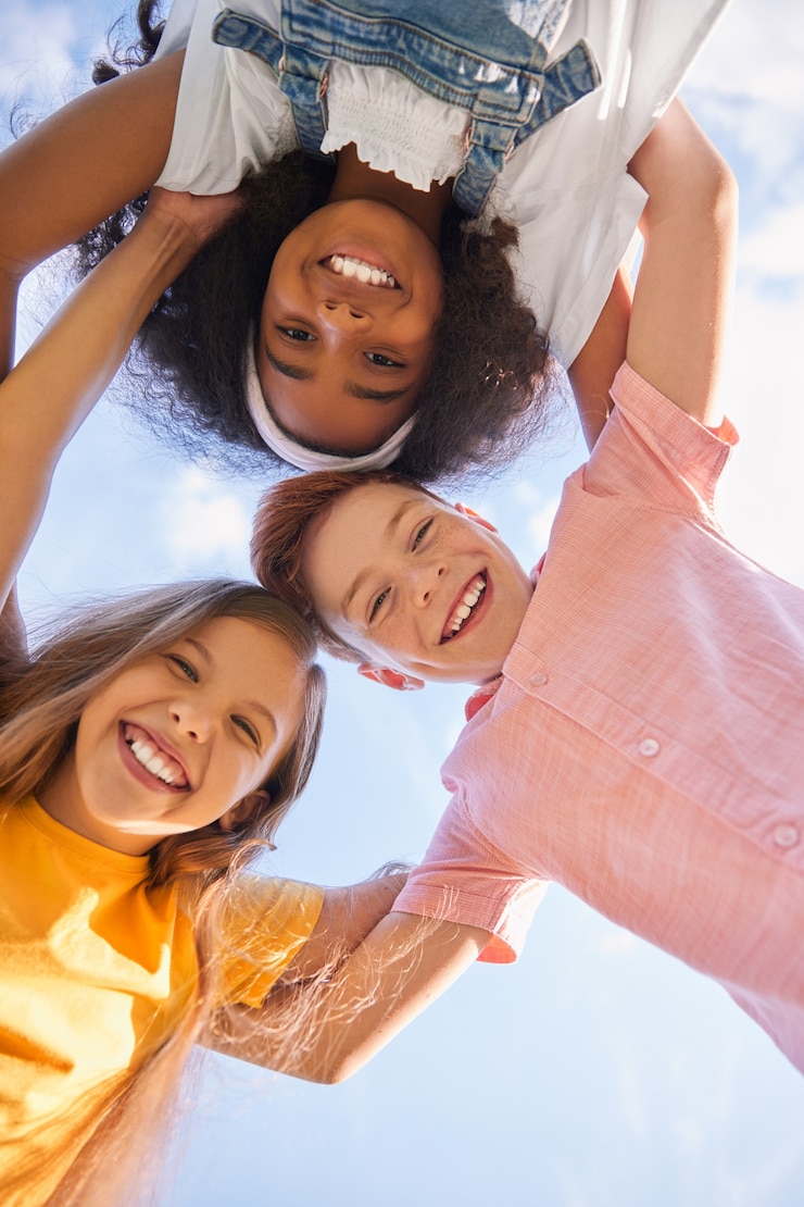 Photo company of diverse children embracing together against blue sky
