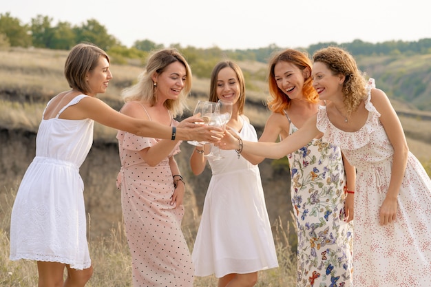 Foto compagnia di amiche si gode un picnic estivo e alza bicchieri di vino