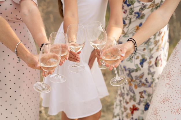 Photo the company of female friends enjoys a summer picnic and raise glasses with wine