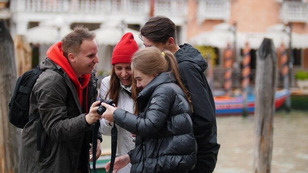 The company of four friends take a selfie and look the picture at the venice waterfront