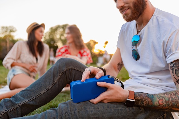 Company of friends having fun together in park listening to music