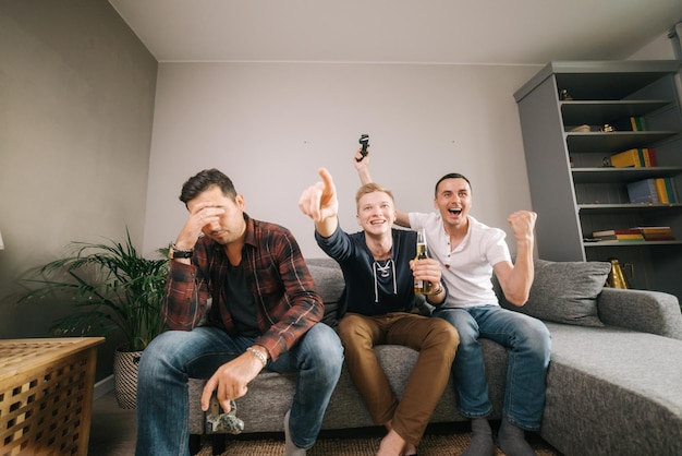 Company of friends is excited to playing video games. Guy is emotionally celebrating the victory over his friend in the console game. Video game and leisure concept