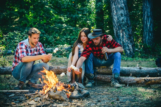 Company friends spend great time picnic or barbecue near\
bonfire camp fire in summer group of happy ...
