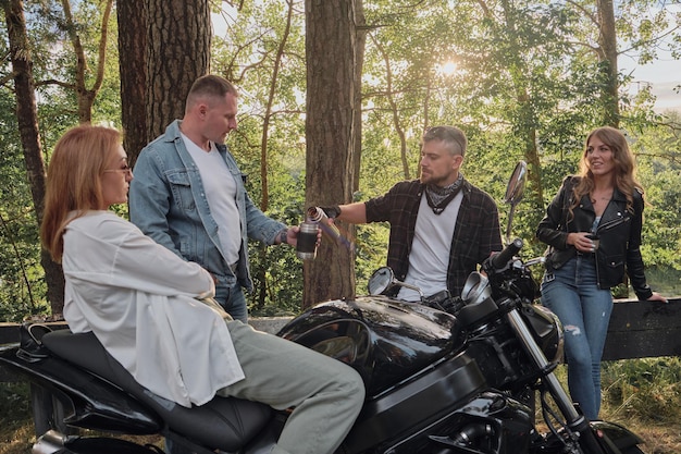 A company of friends travel together on motorcycles stopped at the roadside have fun and drink tea