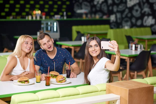 Azienda guardando il telefono e prendendo selfie nella caffetteria